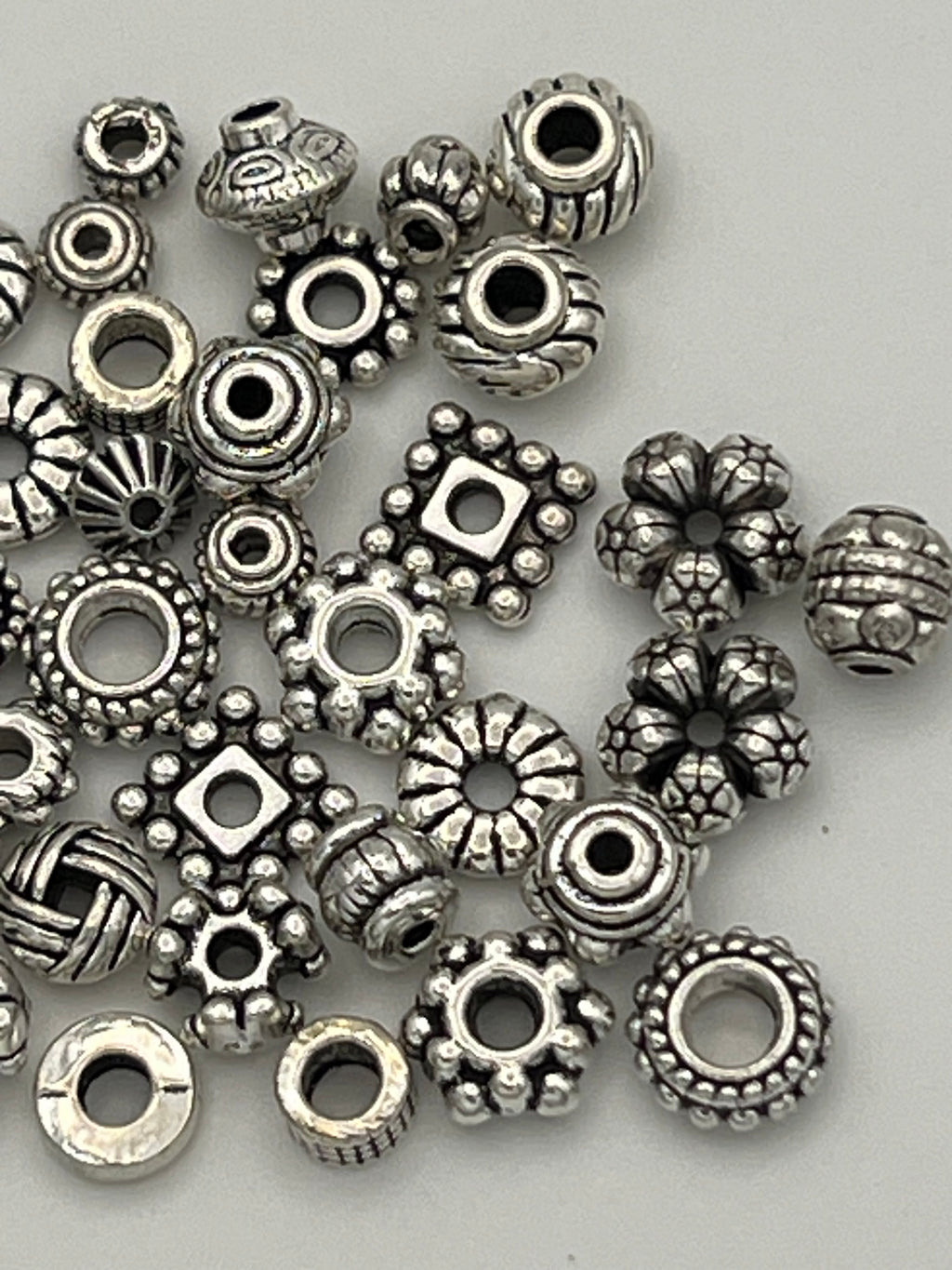 A collection of 50 mixed Tibetan style spacer beads in various shapes and sizes.