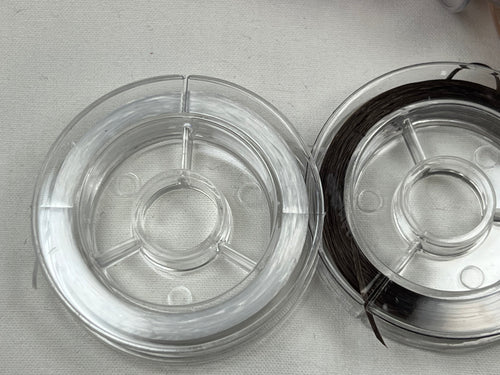 Two spools of elastic string, one white and one dark colored.