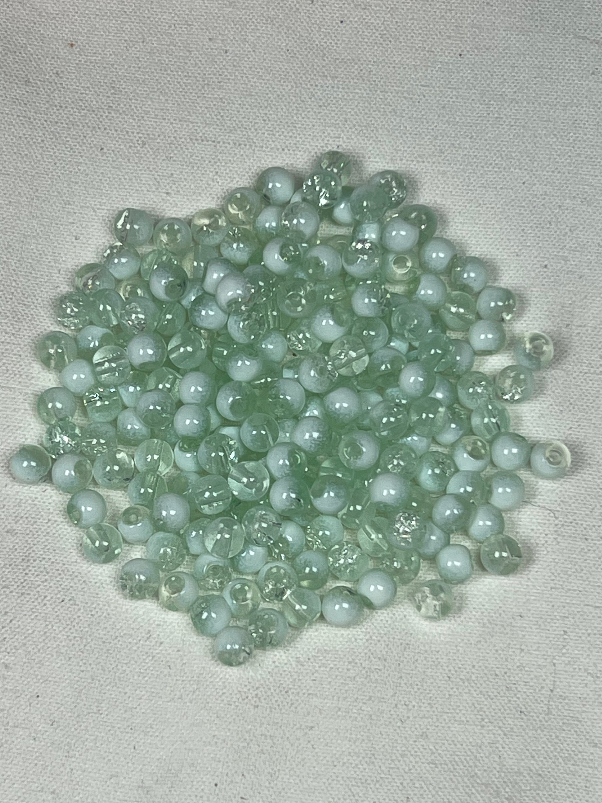 A pile of 300 small, round, translucent azure and white crackle glass beads.