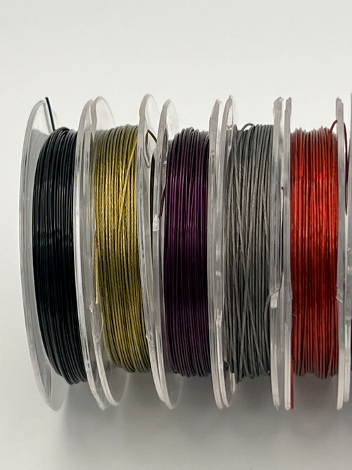 Ten spools of colorful tiger tail wire in black, gold, purple, gray, and red.