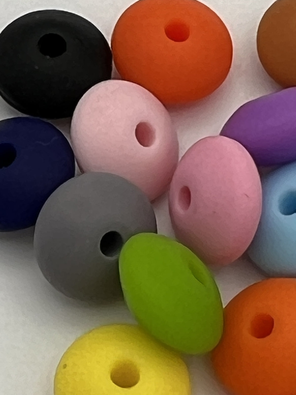 Close-up of 12mm silicone abacus beads in a variety of matte colors including pink, green, and blue.