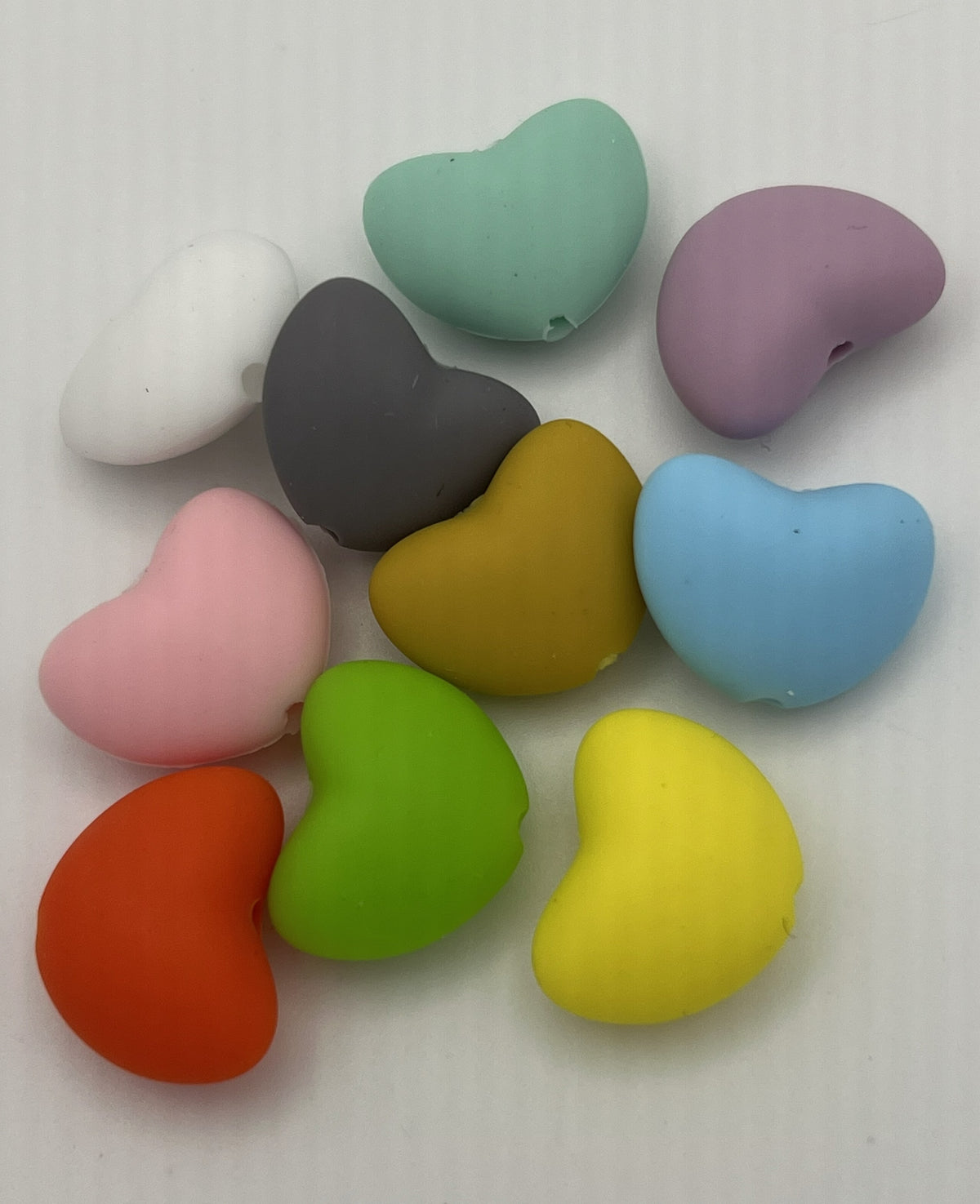 Ten heart-shaped silicone beads in various colors including red, yellow, green, blue, and pink.
