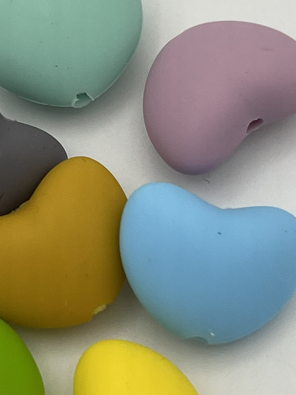 Close-up of colorful silicone heart beads in various shades like blue, yellow, and purple.