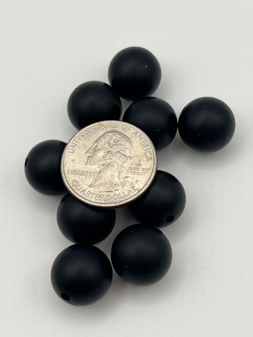 Ten 15mm round black silicone beads are arranged around a quarter.