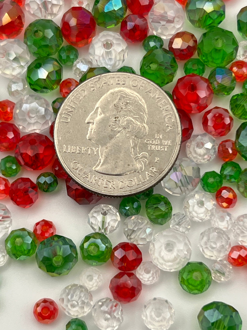 Faceted rondelle glass beads in red, green, and clear, with a quarter for scale.
