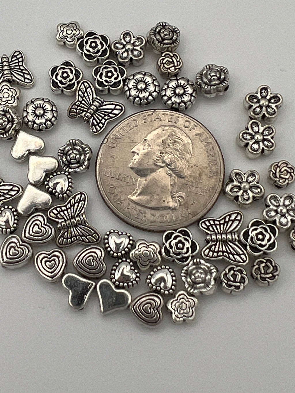 Antique silver Tibetan style beads featuring butterflies, hearts, and flowers in various designs.