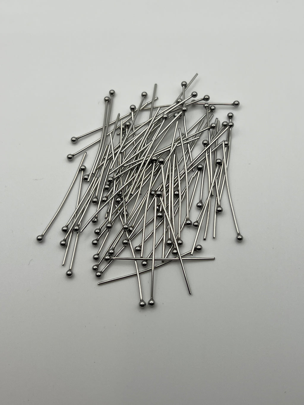 A pile of 75 silver ball head pins on a white background.