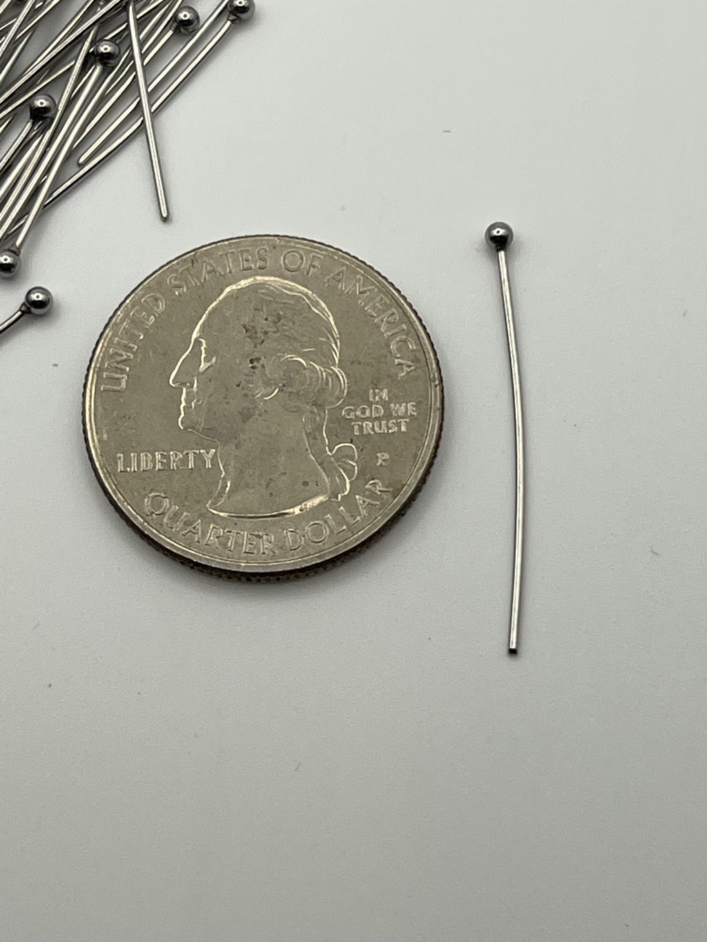 75 30mm 304 stainless steel ball head pins with a quarter.
