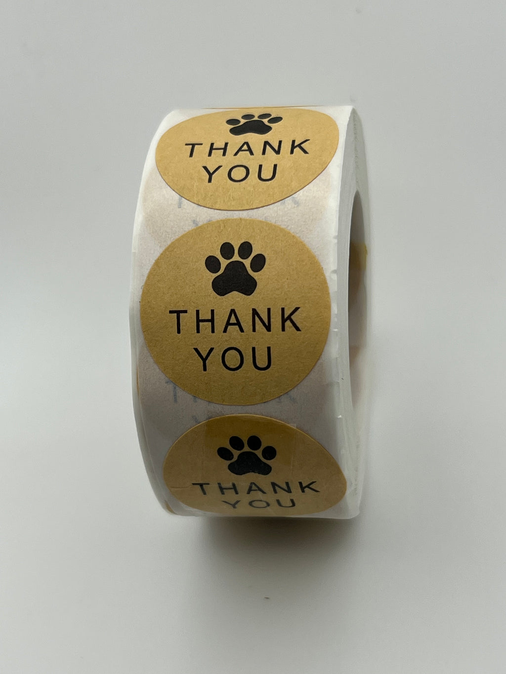 A roll of 500 round kraft brown stickers featuring a black paw print and the words Thank You.