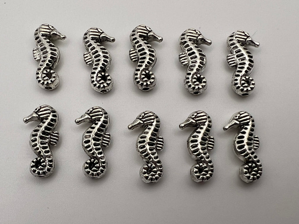 Ten antique silver seahorse beads with intricate detailing.