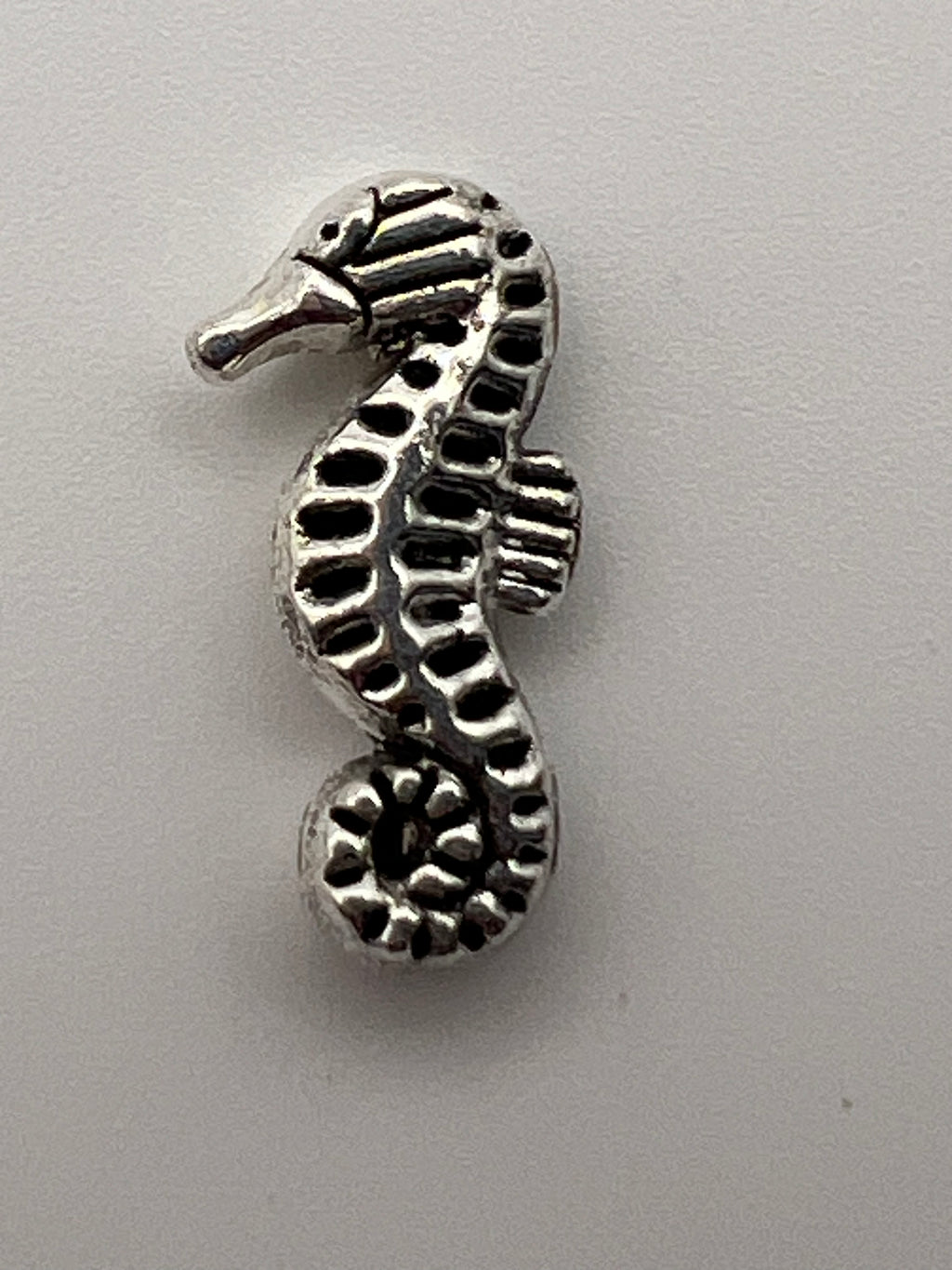 Antique silver seahorse charm with intricate detailing.