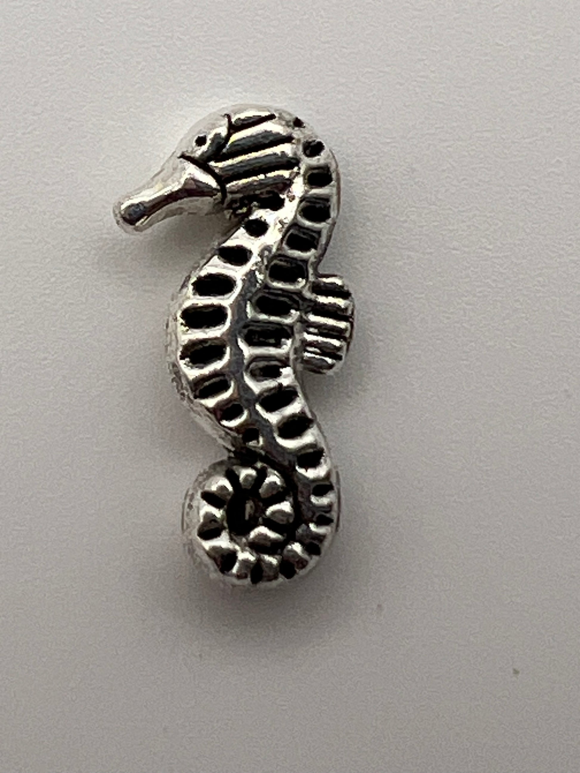 Antique silver seahorse charm with intricate detailing.