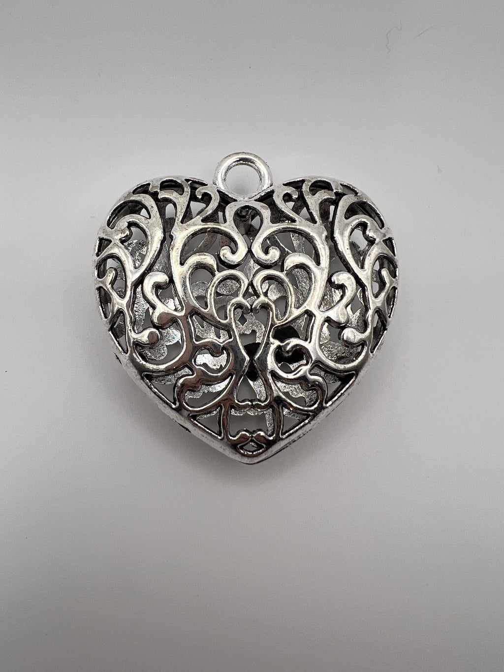 Silver Tibetan style hollow heart pendant with intricate filigree design.