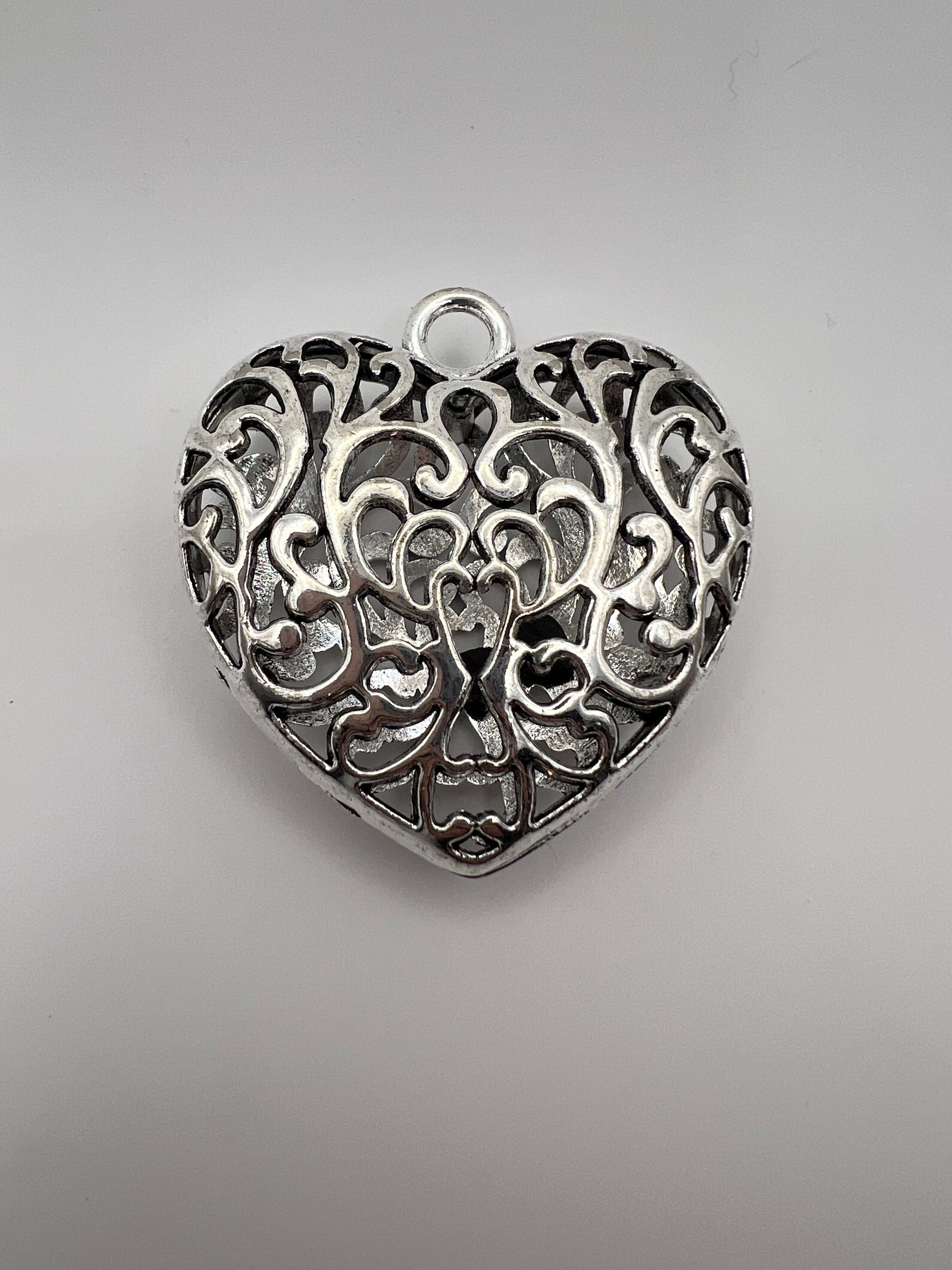 Silver Tibetan style hollow heart pendant with intricate filigree design.
