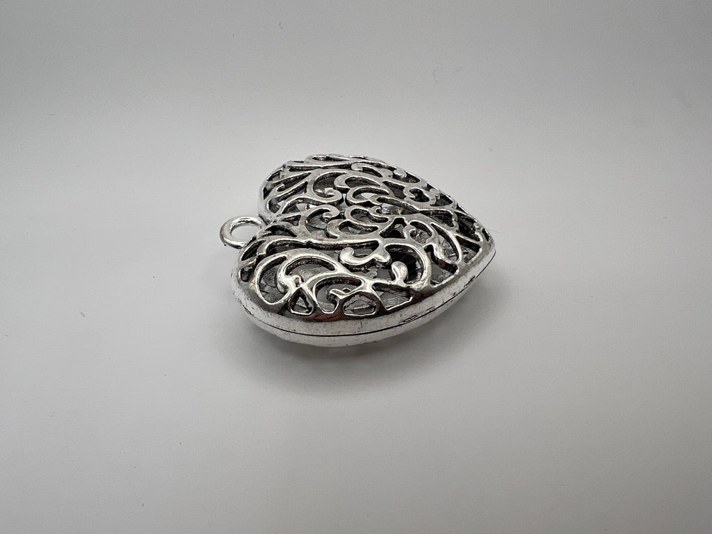 Silver Tibetan style hollow heart pendant with intricate scrollwork.