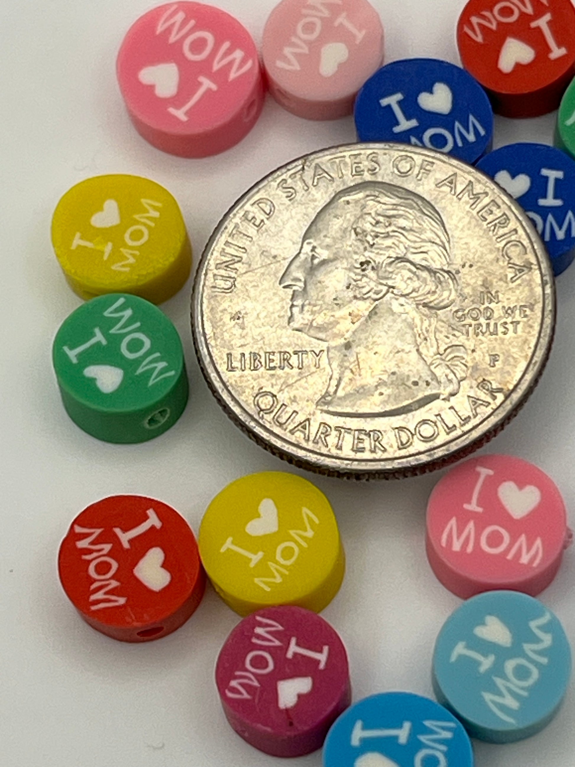 Colorful "I Love Mom" polymer clay beads surround a quarter.