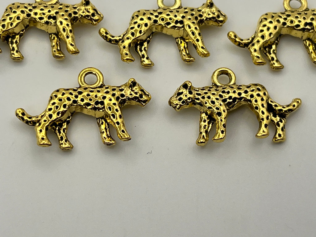 Five antique golden Tibetan style leopard charms with black spots.
