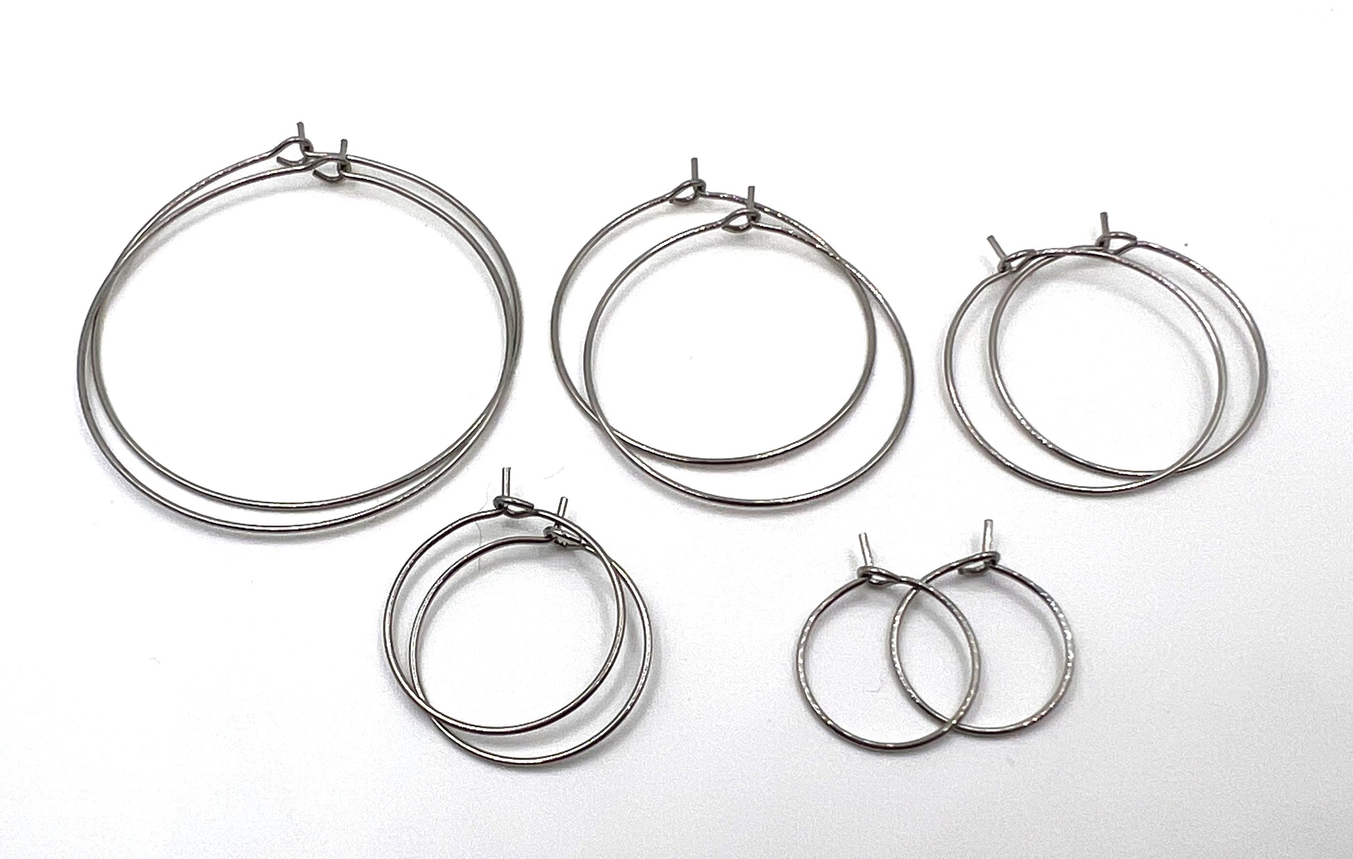 Five sizes of silver stainless steel wine glass charm rings on a white background.