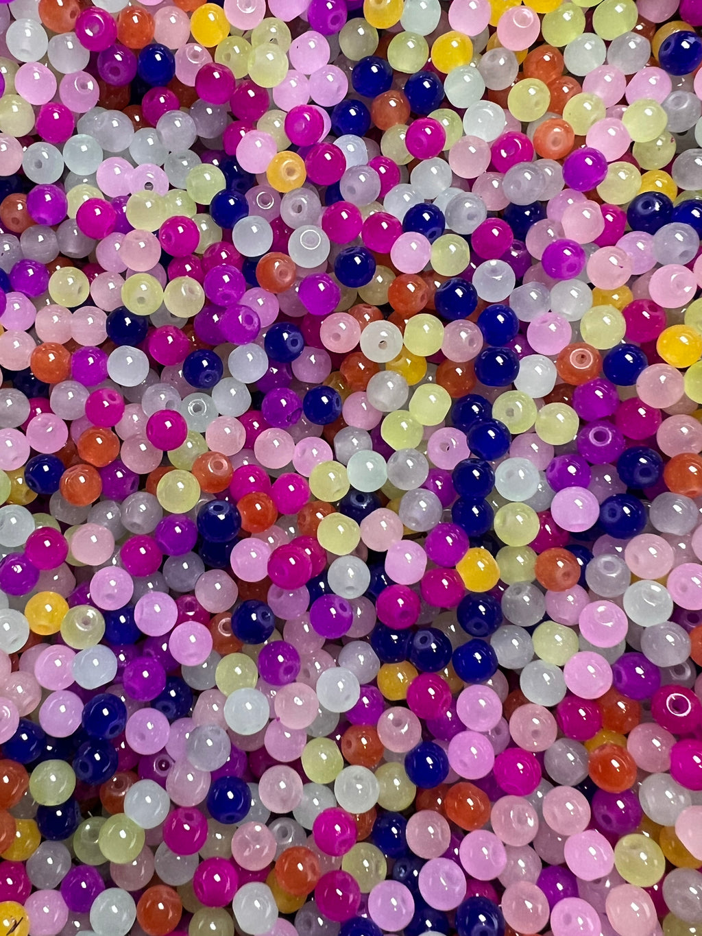 A pile of 6mm round glass imitation jade beads in a variety of vibrant colors.