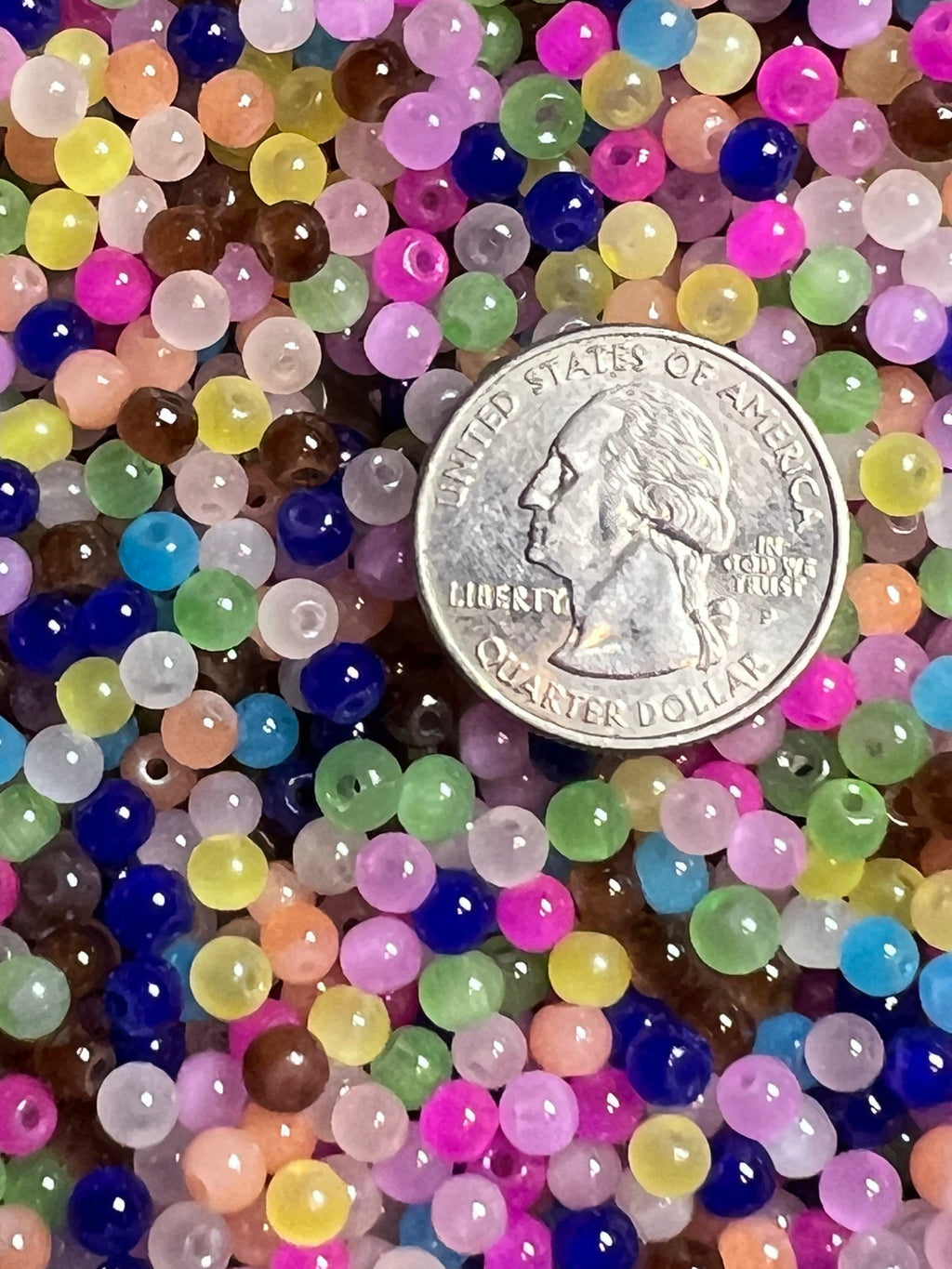 A pile of colorful 4mm glass imitation jade beads shown next to a US quarter for scale.