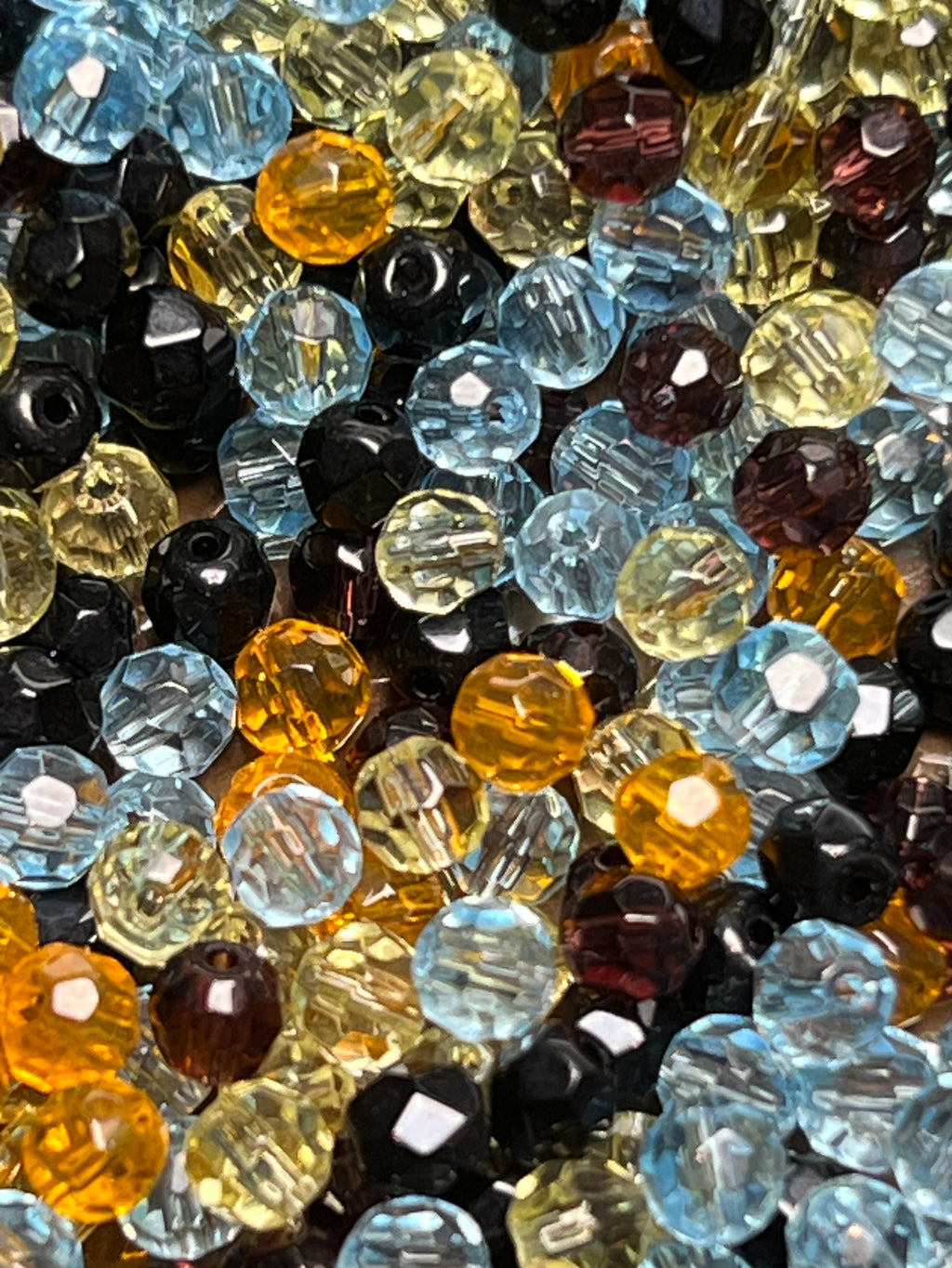 A collection of 4mm faceted glass beads in assorted blue, yellow, black, and brown colors.