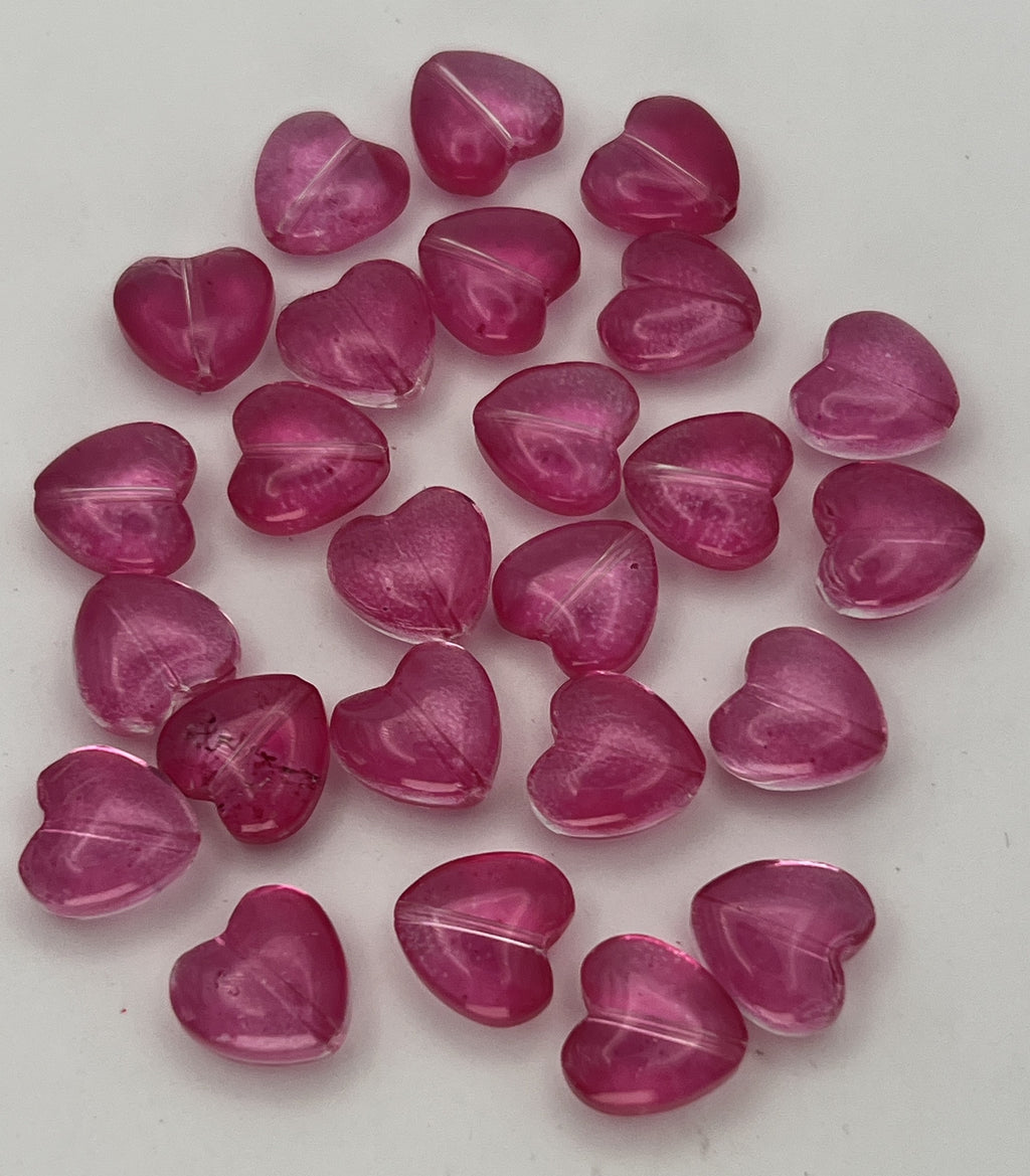 A collection of twenty-five translucent camellia pink glass heart beads for jewelry making.