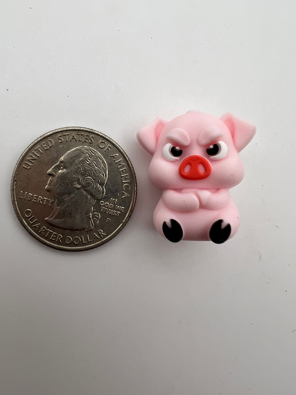 Pink angry pig silicone focal bead next to a US quarter for scale.