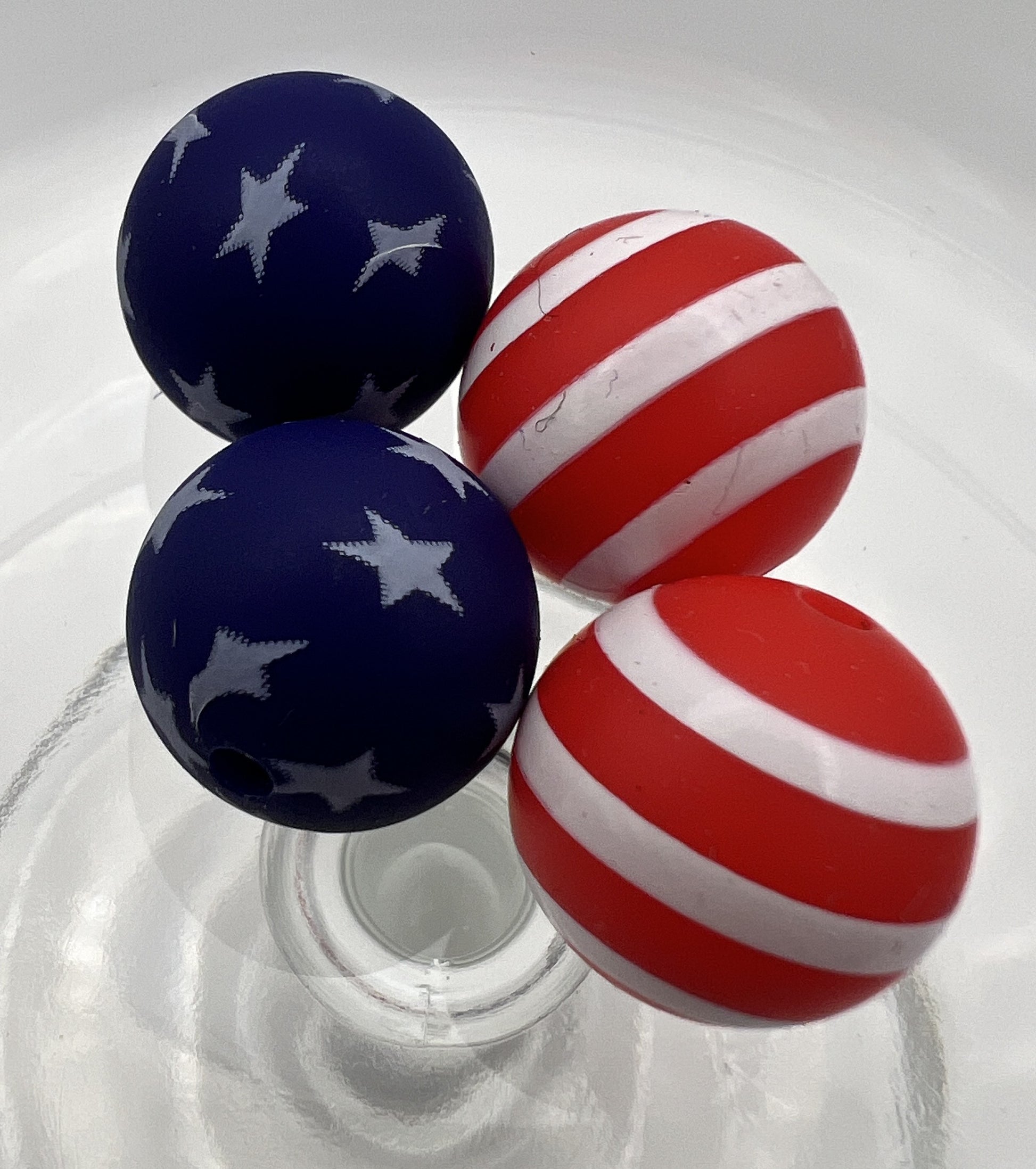 Four 15mm silicone beads featuring two blue star-patterned and two red-and-white striped designs.
