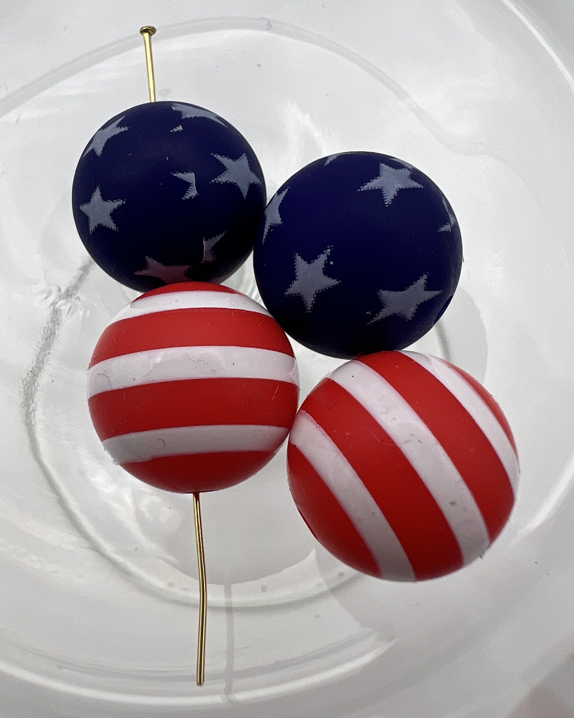 Four 15mm silicone beads featuring two blue star-patterned and two red-and-white striped designs.
