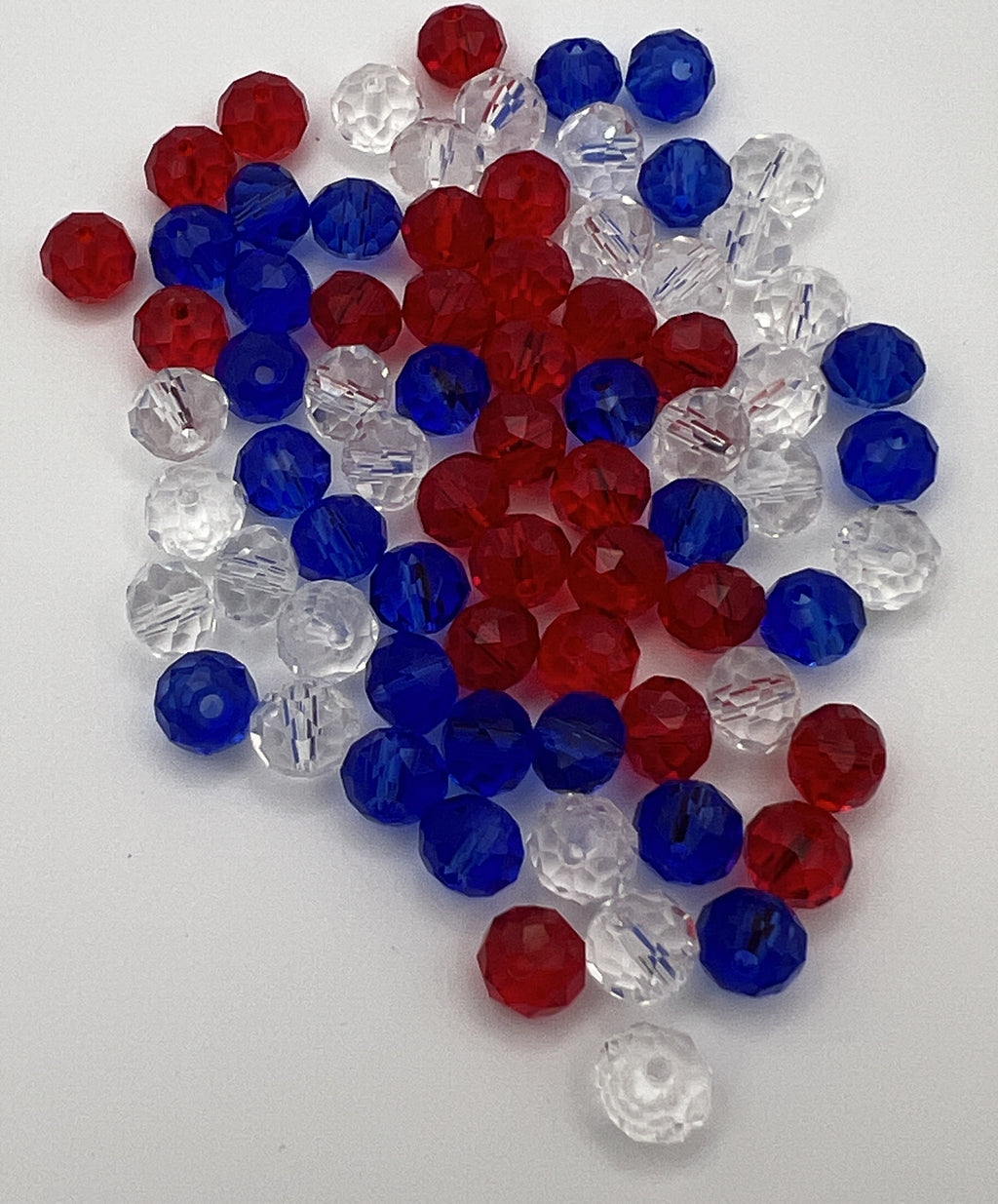 A pile of faceted glass rondelle beads in a patriotic mix of red, white, and blue.
