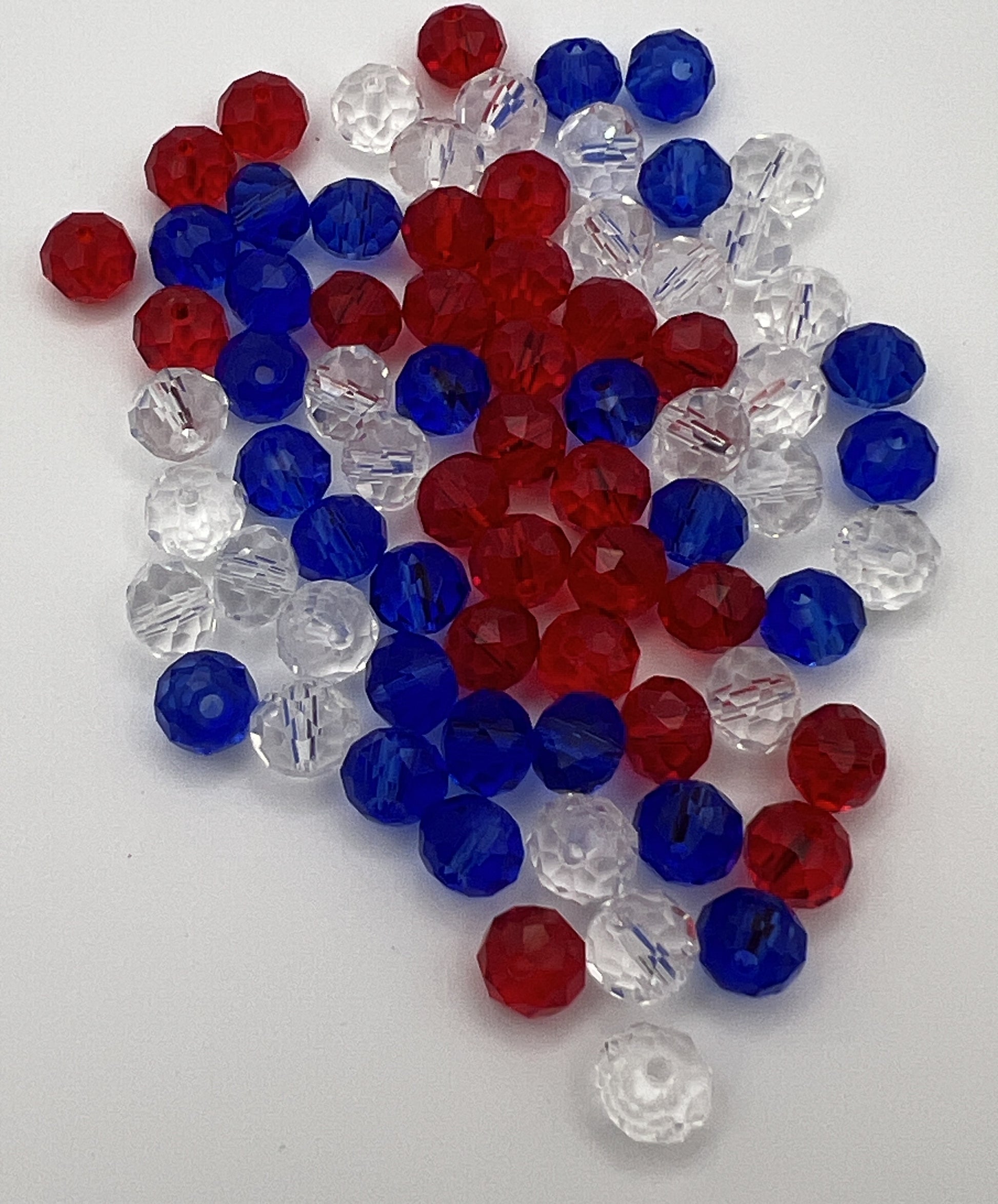 A pile of faceted glass rondelle beads in a patriotic mix of red, white, and blue.
