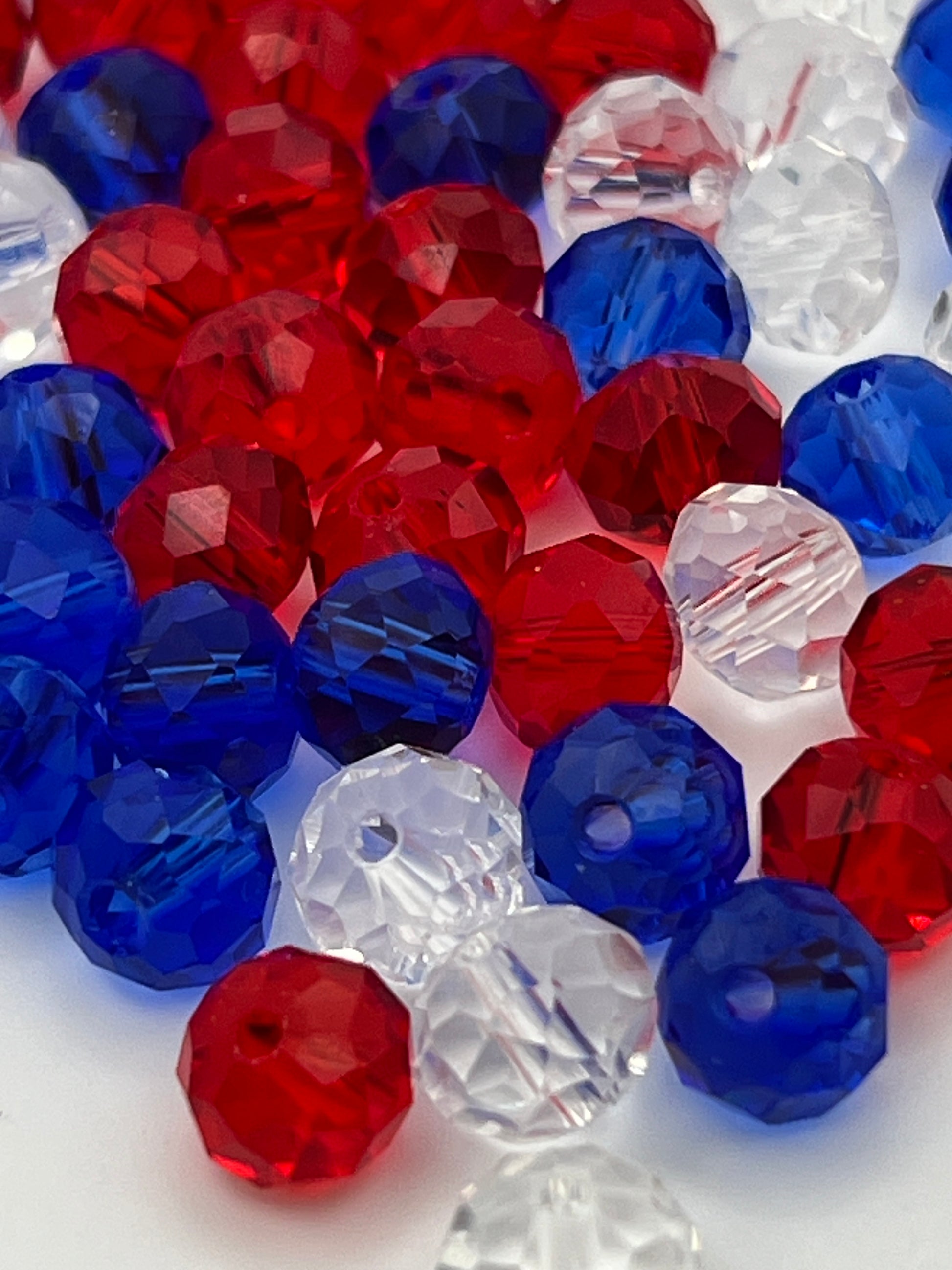 A pile of faceted glass rondelle beads in red, white, and blue colors.
