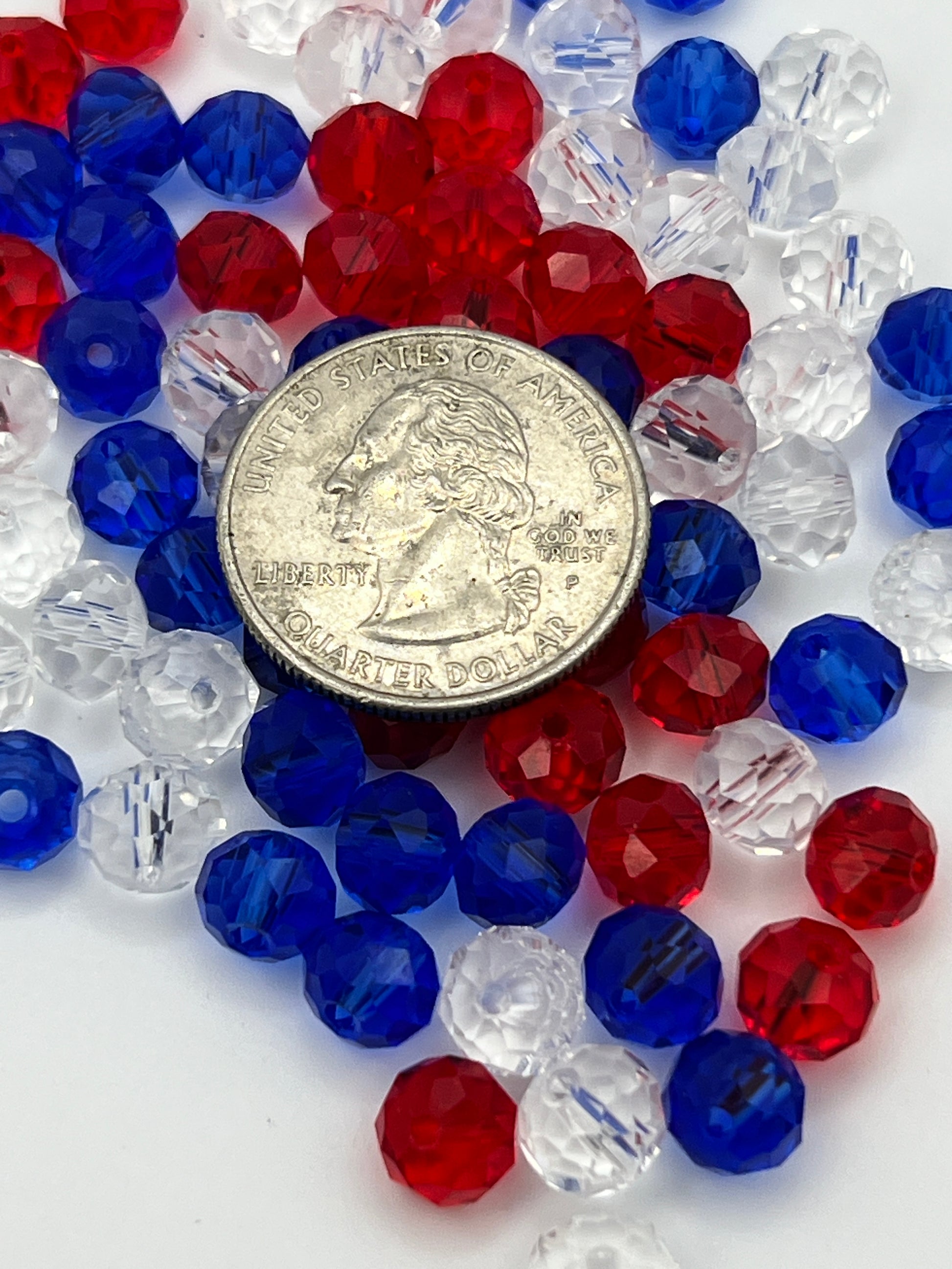 A pile of red, white, and blue faceted glass rondelle beads shown next to a US quarter.