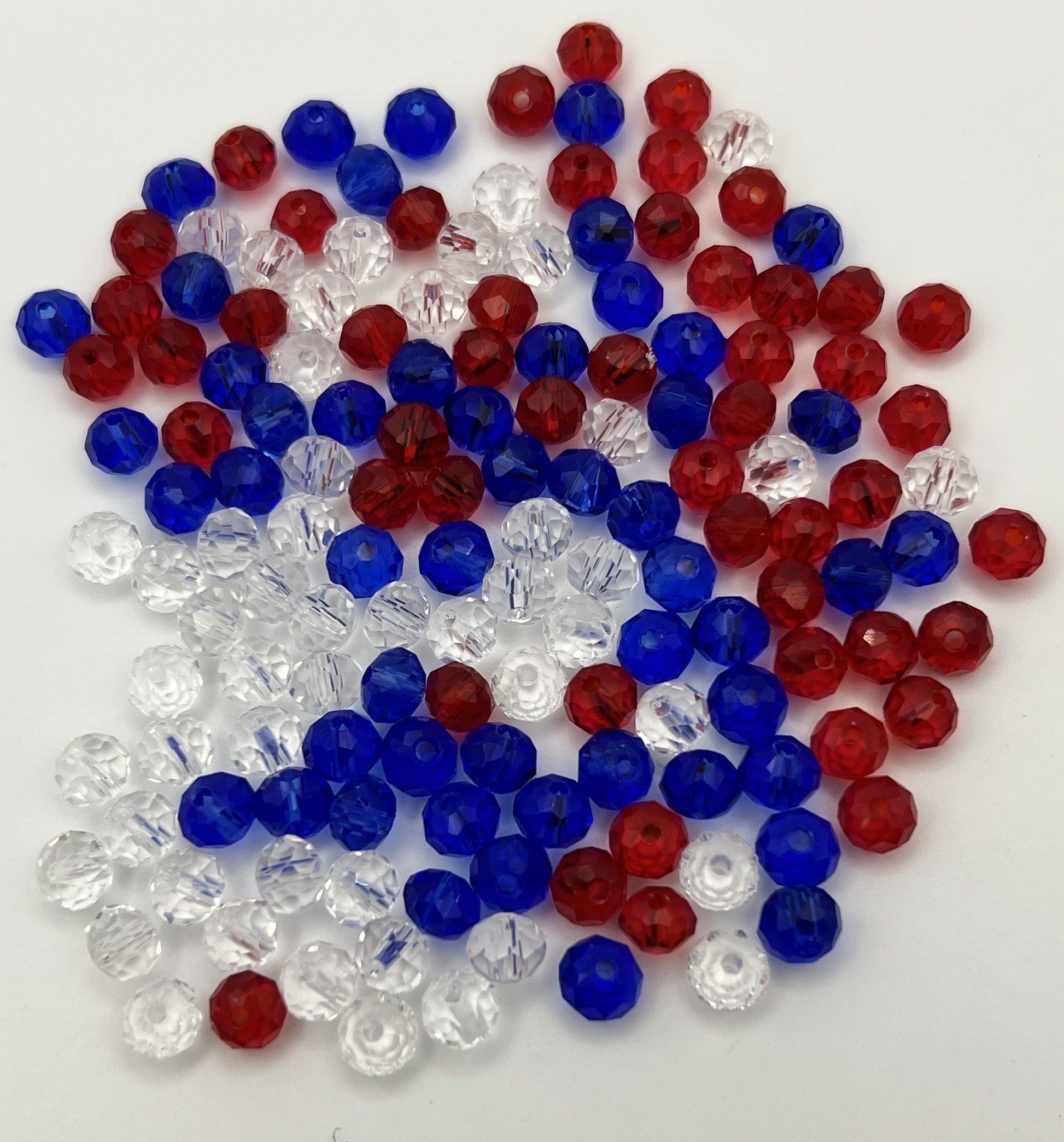 A pile of 150 faceted glass rondelle beads in red, white, and blue colors.