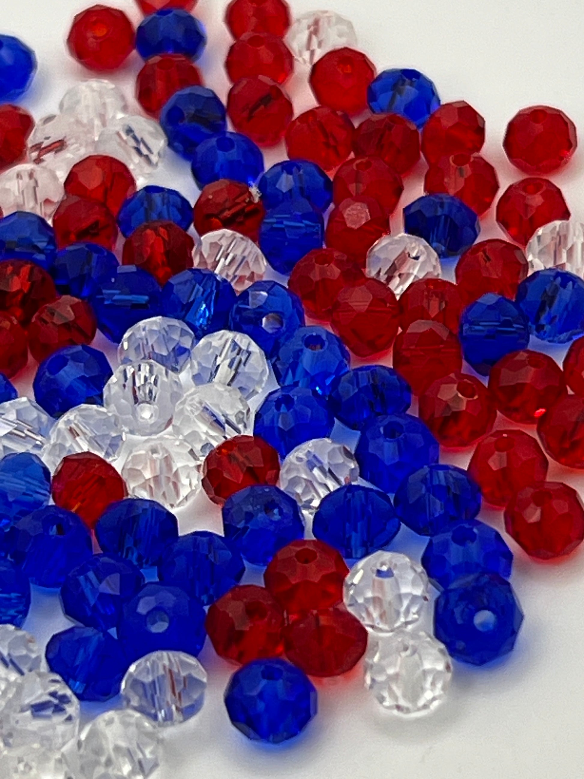 A pile of red, white, and blue faceted glass rondelle beads on a white background.