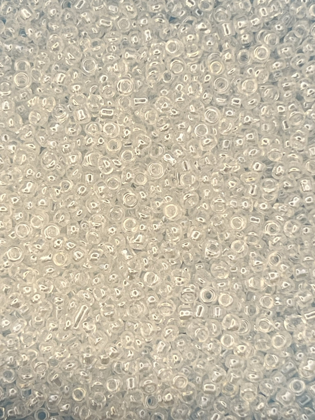 Close-up of 12/0 white transparent lustered glass seed beads in a bulk pile.