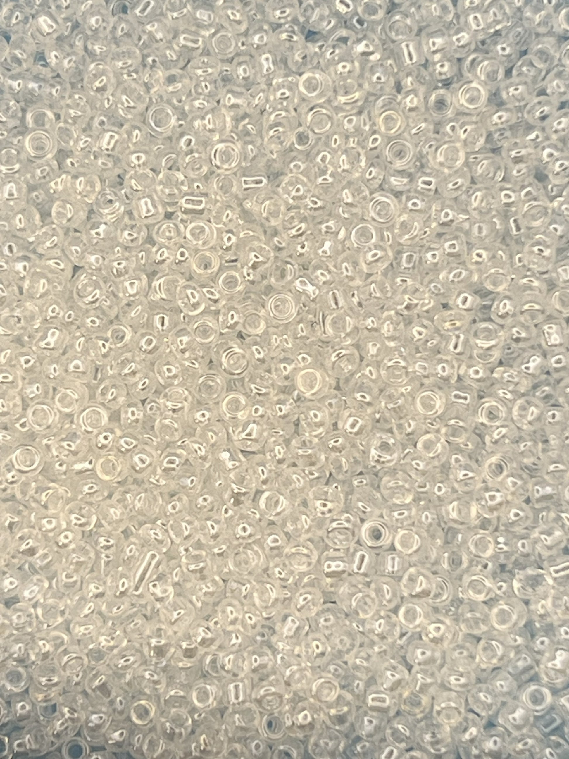Close-up of 12/0 white transparent lustered glass seed beads in a bulk pile.