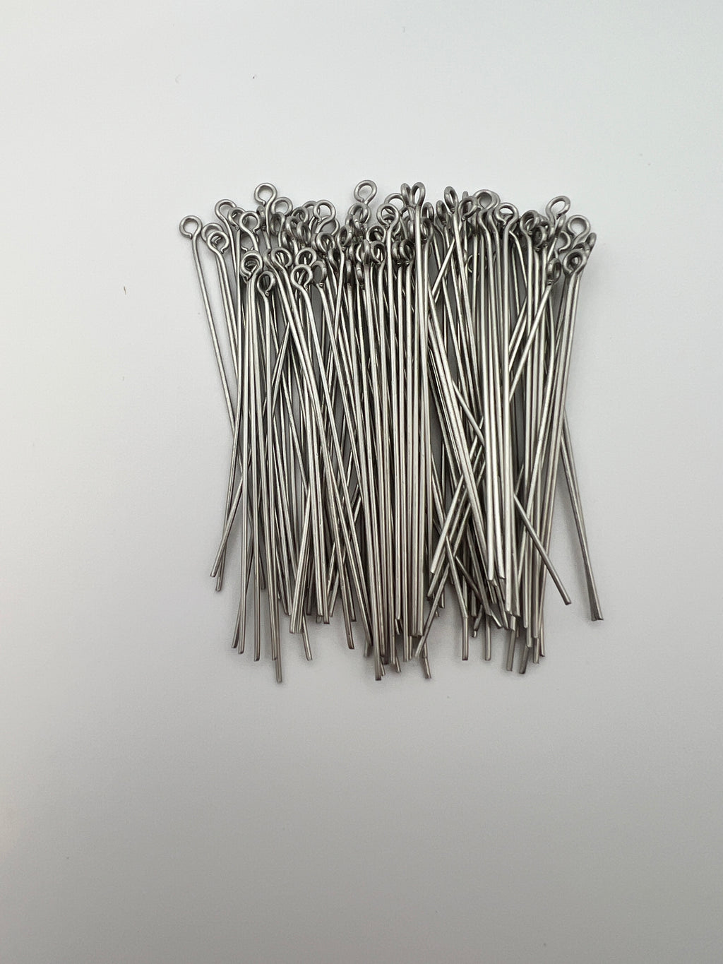 A bulk bag of 50mm 304 stainless steel eye pins for jewelry making on a white background.