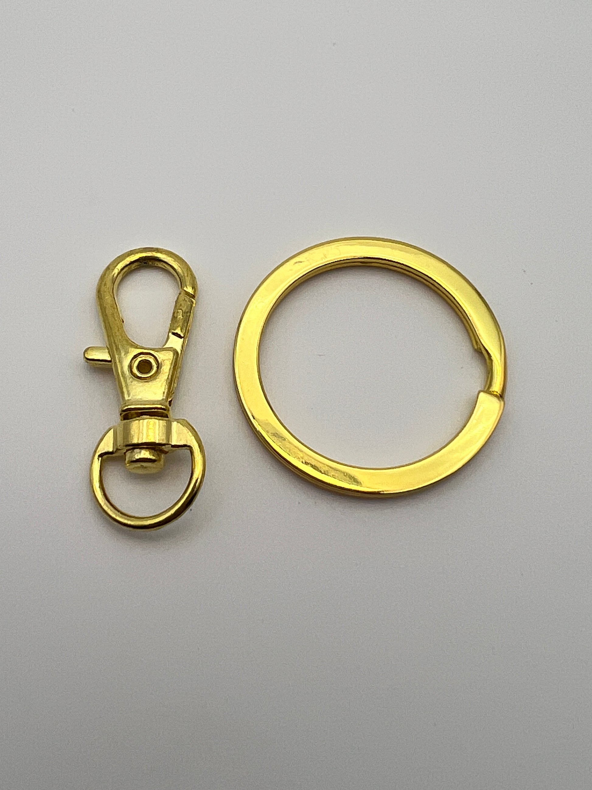 Golden split key ring next to a swivel lobster clasp on a plain white background.