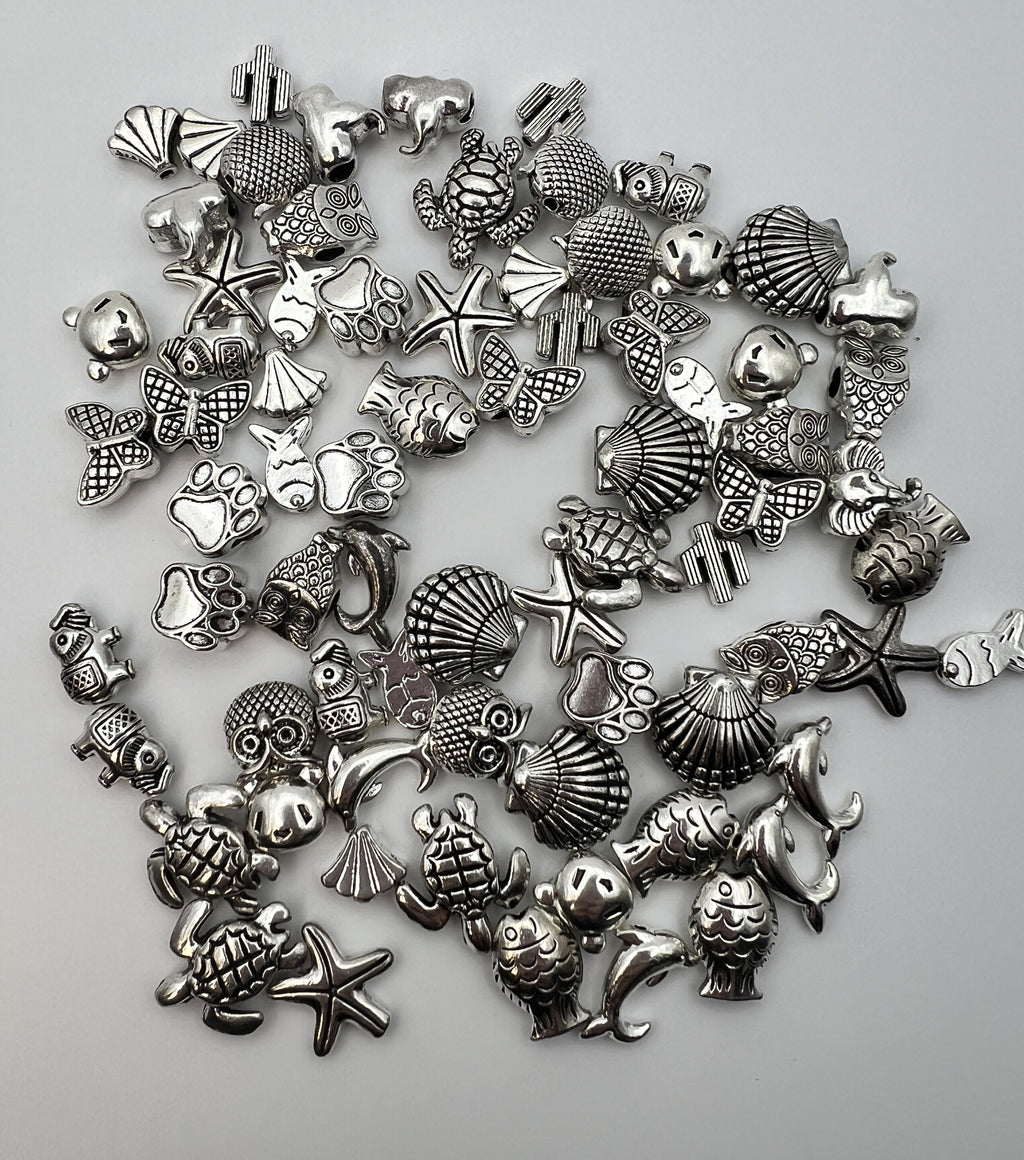 Assorted silver Tibetan style beads in 15 designs including owls, turtles, fish, and shells.
