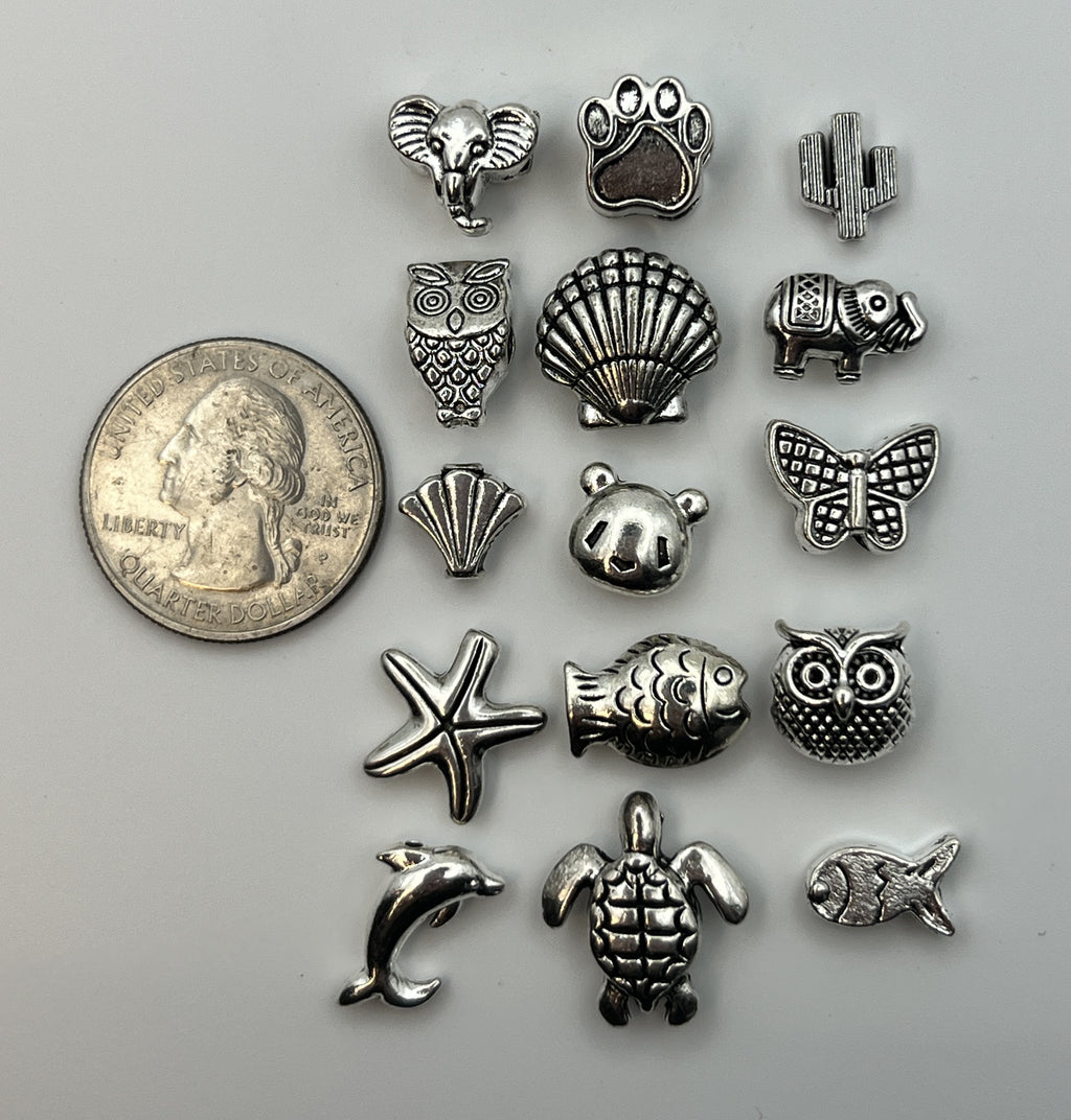 Assorted silver Tibetan style beads in animal and nature shapes next to a US quarter for scale.