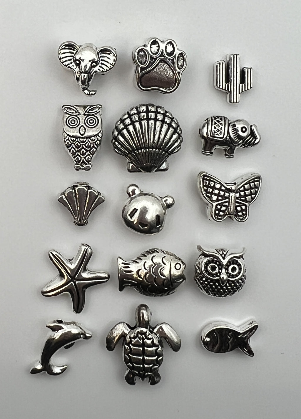 Assortment of 15 unique antique silver Tibetan style beads featuring animals and nature designs.