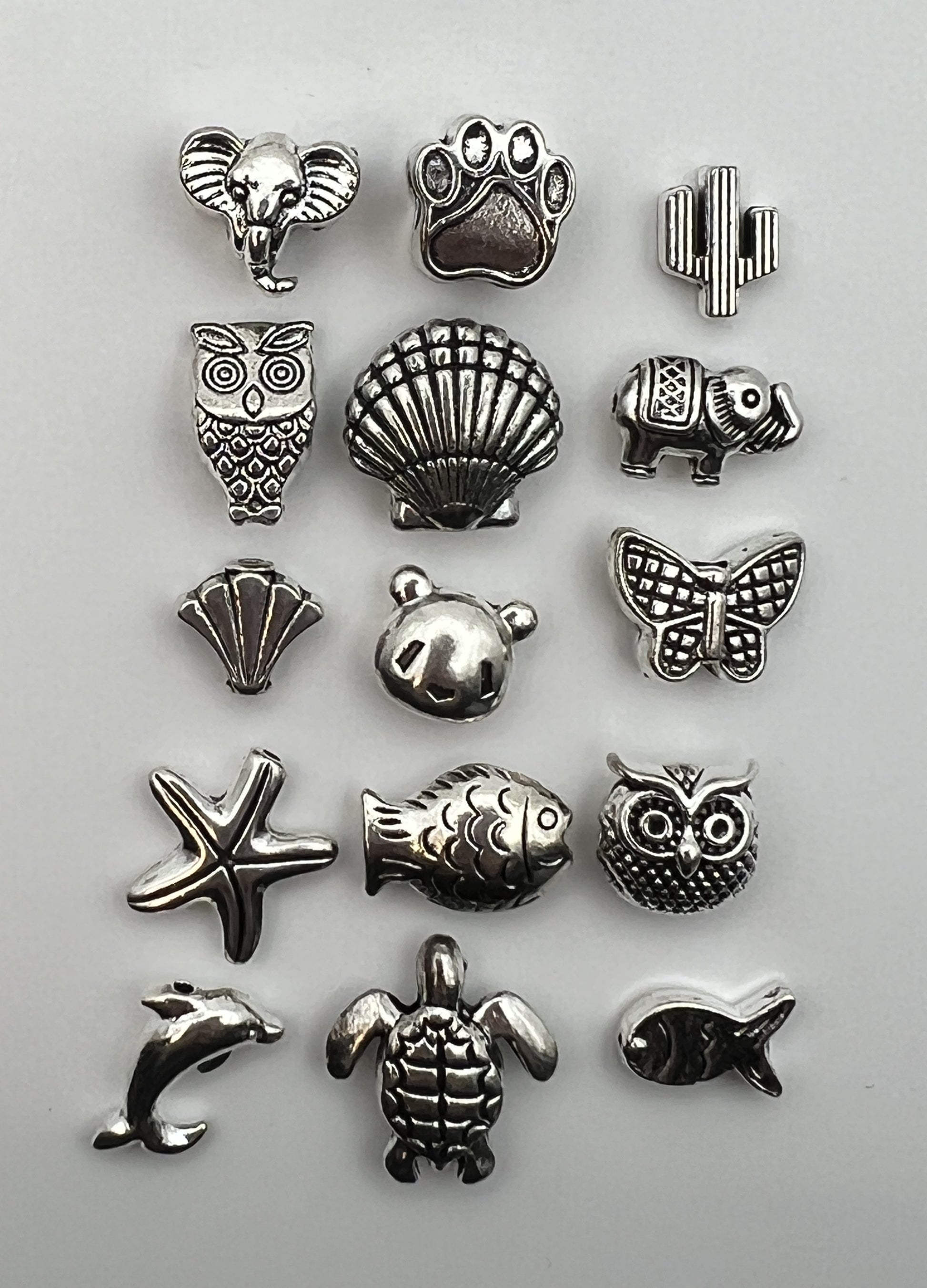 Assortment of 15 unique antique silver Tibetan style beads featuring animals and nature designs.