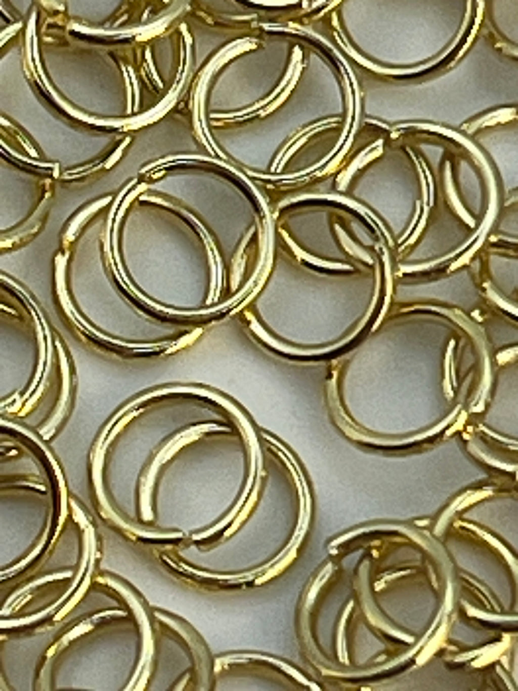 A pile of 5mm golden 304 stainless steel jump rings.
