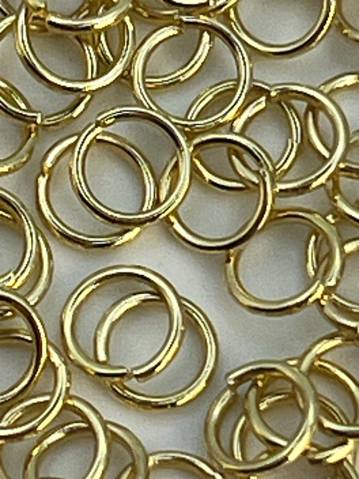 A pile of 5mm golden 304 stainless steel jump rings.
