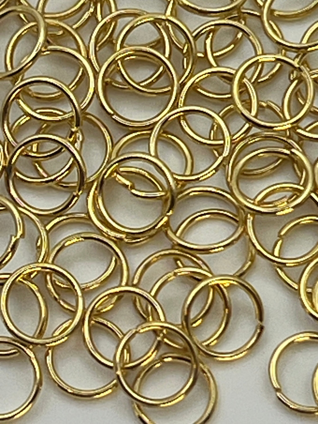 A pile of 6mm golden 304 stainless steel jump rings.