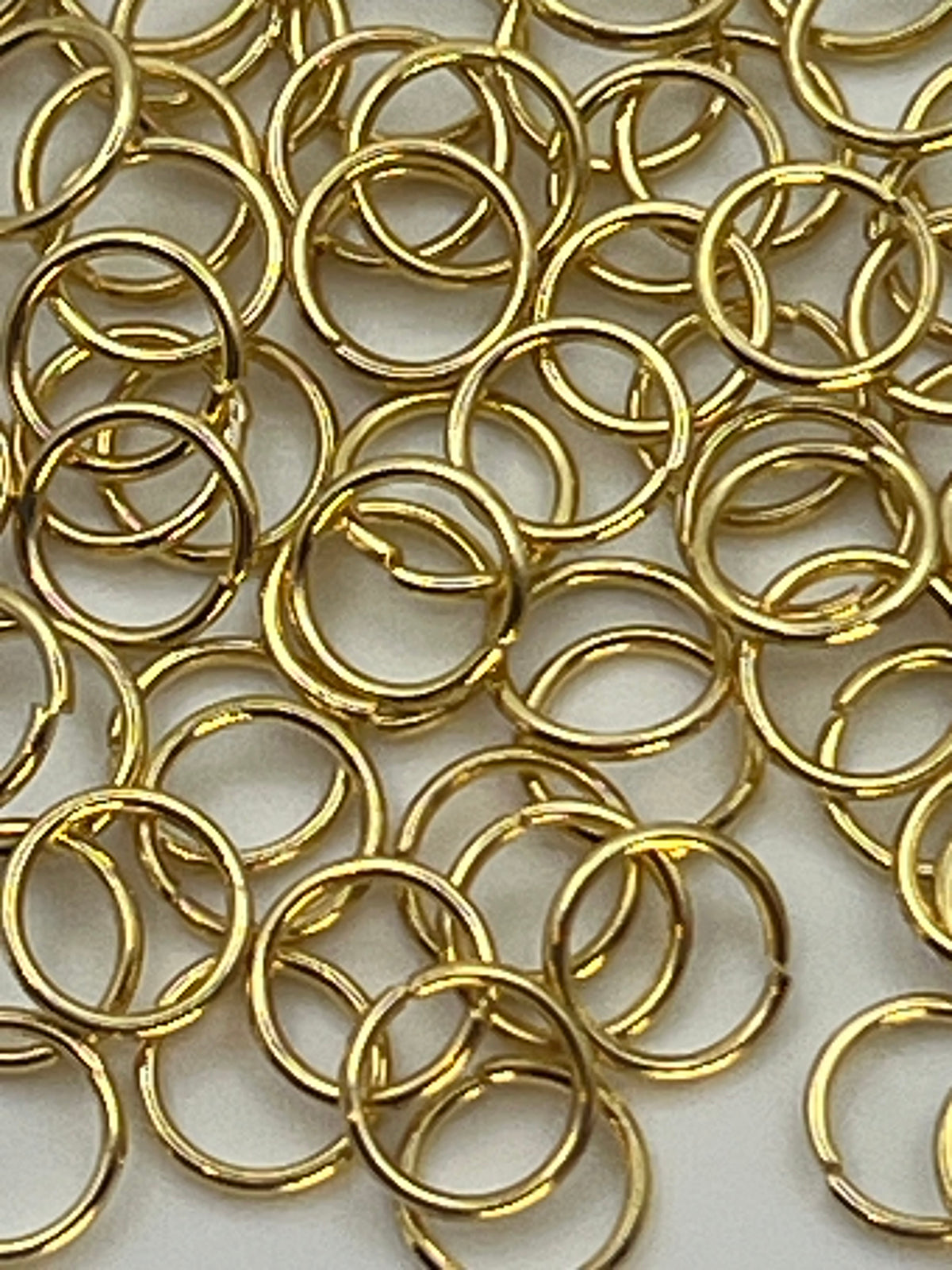 A pile of 6mm golden 304 stainless steel jump rings.