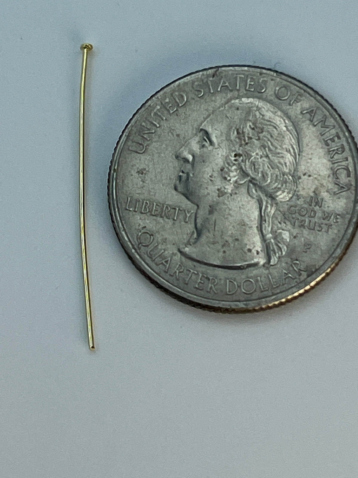 A single 30mm gold-plated flat head pin next to a quarter.
