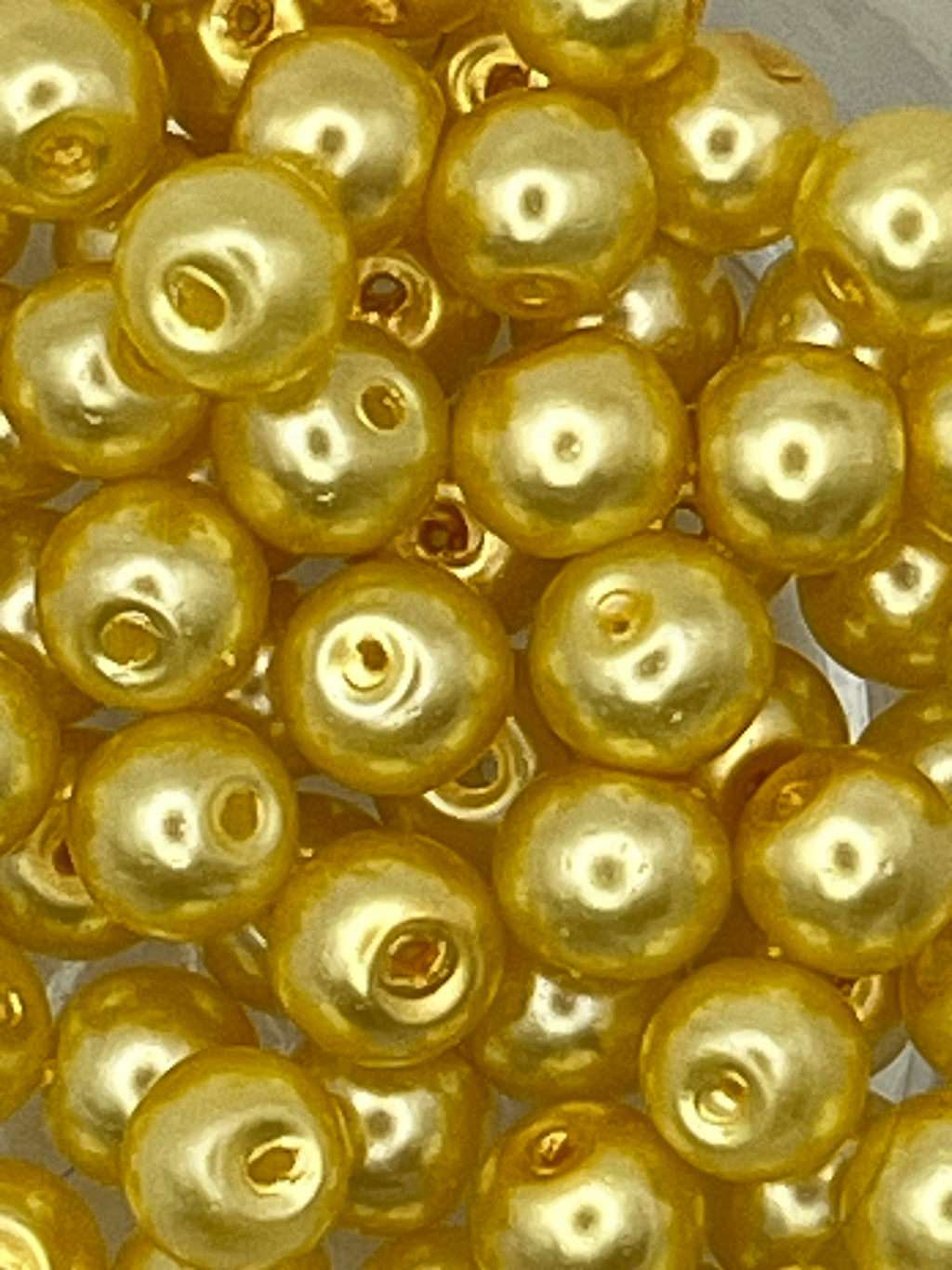 Close-up of 6mm yellow glass pearl beads for jewelry and craft making.