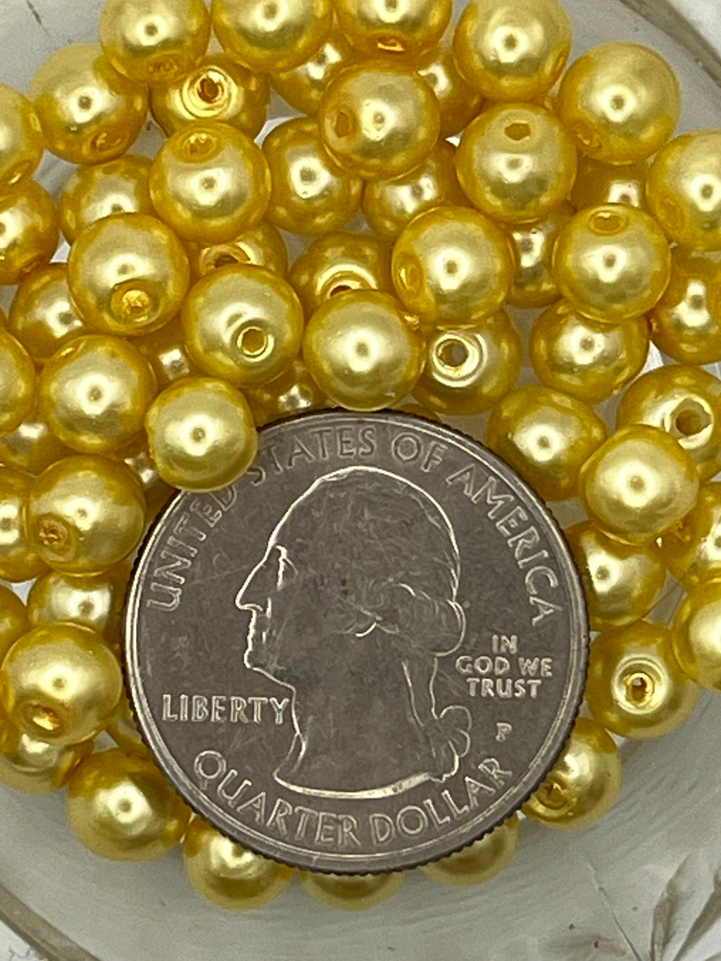 6mm yellow glass pearl beads shown next to a US quarter for size comparison.